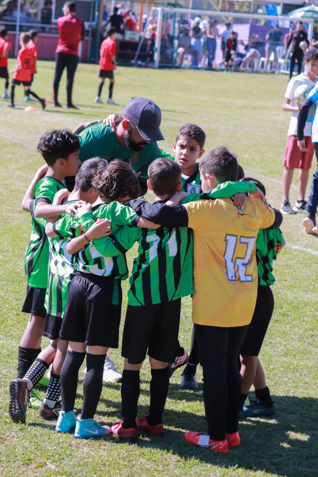 Alunos do sub 9 da América Mineiro reunidos em roda com o professor durante o treino